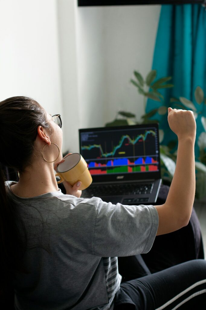 Stock market and investing concept with trader working on laptop. Businesswoman celebrating.