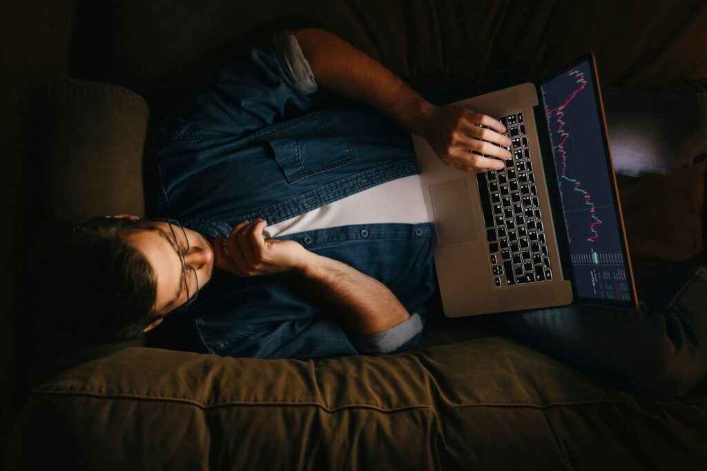 Young stock exchange trader broker looking at laptop screen at home